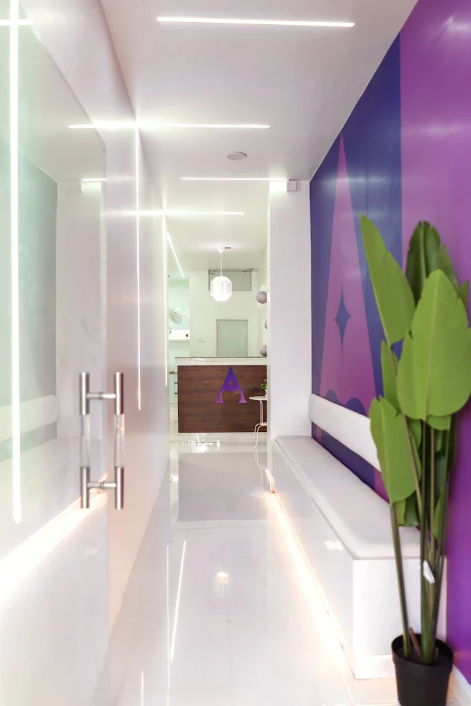 Illuminated modern hallway at Asha Dental Clinic with purple brand wall and comfortable waiting bench