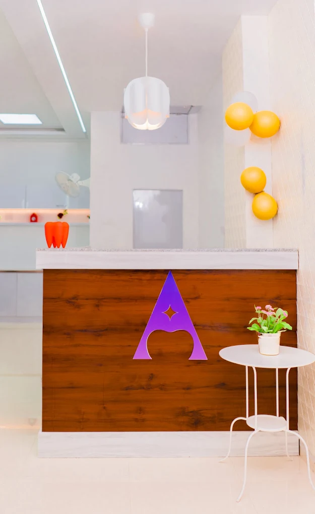 Asha Dental Clinic reception counter featuring warm wood finish and custom purple logo emblem